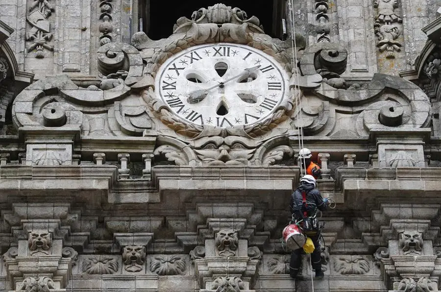 Los operarios limpian la fachada de la torre del reloj de la catedral de Santiago. - EFE