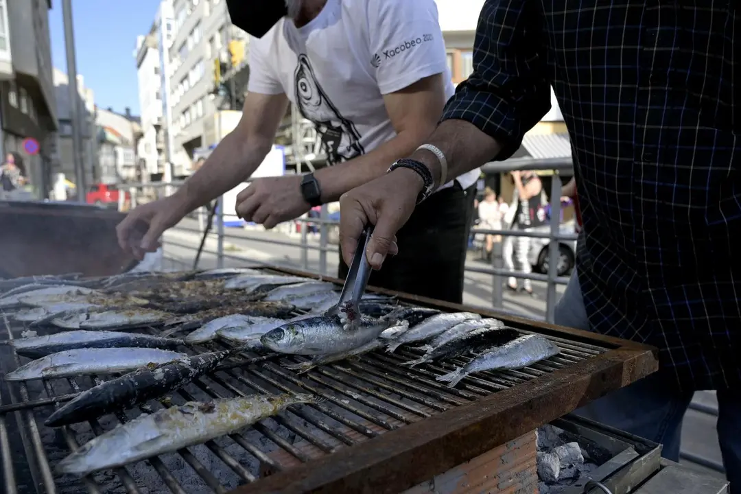 Dos hombres asan sardinas por la festividad de San Juan. - Europa Press