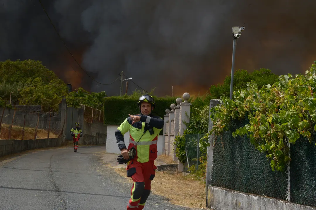 Bomberos se retiran del acceso a unas viviendas del Alto del Cumial, por la imposiblidad de acercarsse al fuego por esa v&iacute;a. en la extinci&oacute;n incendio de Seixalbo. | Rosa Veiga