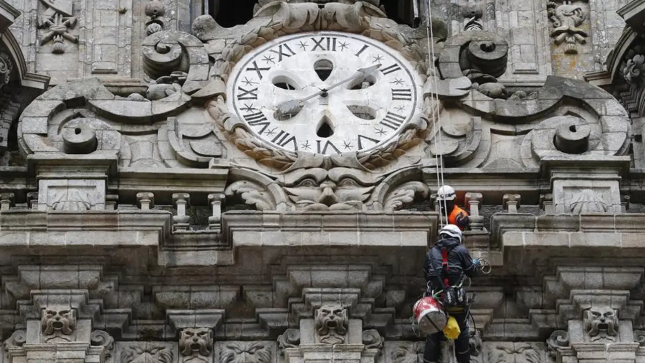 Los operarios limpian la fachada de la torre del reloj de la catedral de Santiago. - EFE