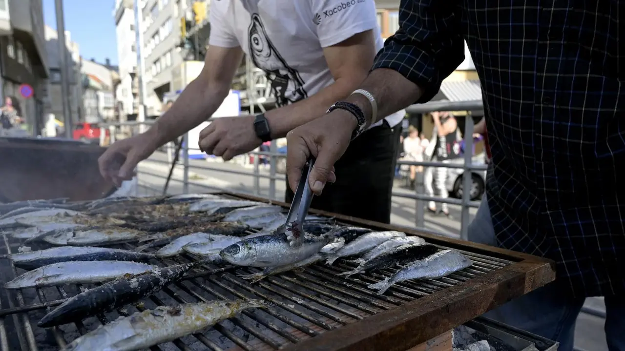 Dos hombres asan sardinas por la festividad de San Juan. - Europa Press