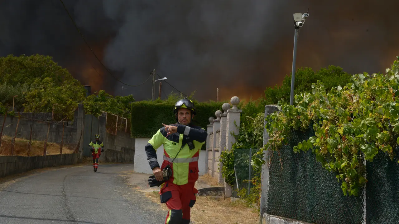 Bomberos se retiran del acceso a unas viviendas del Alto del Cumial, por la imposiblidad de acercarsse al fuego por esa v&iacute;a. en la extinci&oacute;n incendio de Seixalbo. | Rosa Veiga